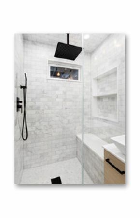 A shower detail with white marble subway tile walls and niche, marble herringbone tile fooring, and a black faucet and showerhead.