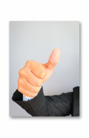 Business man in suit with red tie showing thumbs up sign on gray background.