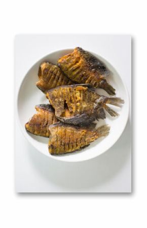Fried fish in a white plate on a white background, top view