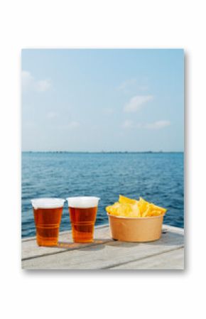cups with beer and some potato chips on a dock