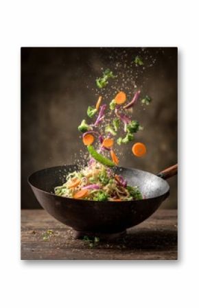 Colorful vegetables and noodles being tossed in a hot wok.