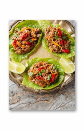 Beef cups or minced meat lettuce wraps on close-up on plate on table. Vertical top view from above