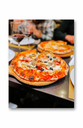 Enjoying delicious pizzas with friends at an Italian restaurant in the evening