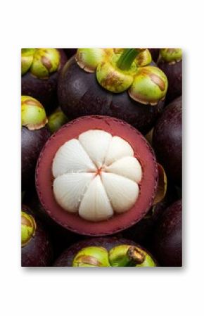 A close-up showcases vibrant mangosteen fruits, offering a glimpse of its juicy, white segments amidst a pile of fresh, purple mangosteens.