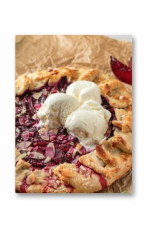 French Galette or pie with plums and almonds served with ice cream scoops close up on parchment paper. Summer traditional homemade sweet pastries