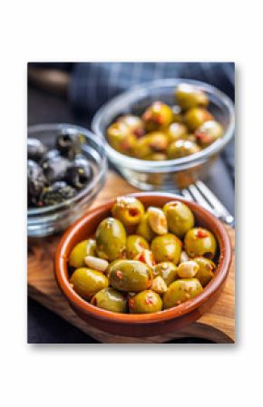 Tapas. Flavored pickled olives in bowl on cutting board.