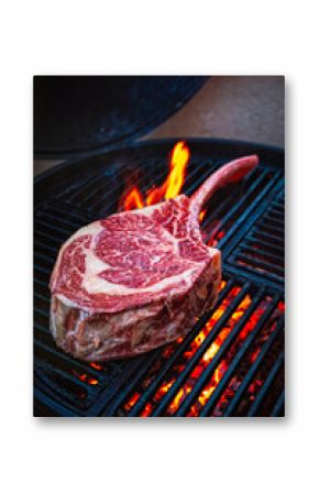 Barbecue dry aged angus tomahawk steak as close-up on a charcoal grill with fire and smoke