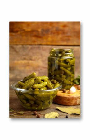Glass bowl with tasty pickled cucumbers and different spices on wooden background