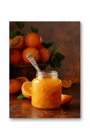Orange jam and fresh fruits on a brown vintage table.