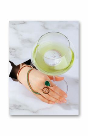 female hand with jewelry holding alcoholic fruit cocktail in hand