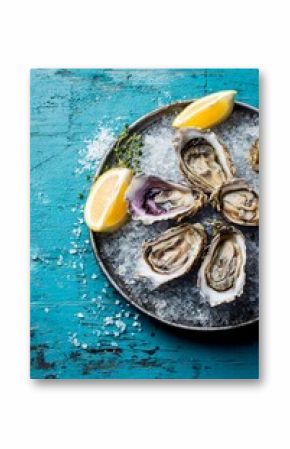 A beautiful platter of fresh oysters rests on crushed ice, garnished with lemon wedges and thyme. The vibrant turquoise surface enhances the appealing display