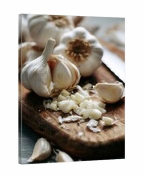 Chopped garlic sits on a wooden board next to whole bulbs and cloves in the kitchen