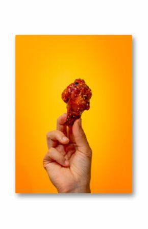 Hand holding fried chicken wing on bright background