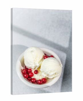 Vanilla ice cream scoops in bowl with fresh red currants on light background