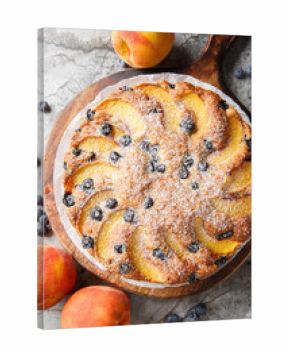 blueberry peach cake is soft, moist, and bursting with juicy fruit flavor closeup on the wooden board on the table. Vertical top view from above