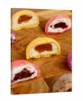 Assorted colorful mochi ice cream halves on wooden board, close-up view, studio lighting