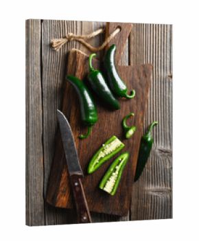 Black jalapeno with knife on rustic wooden cutting board close up. Green mexican jalapeno hot peppers