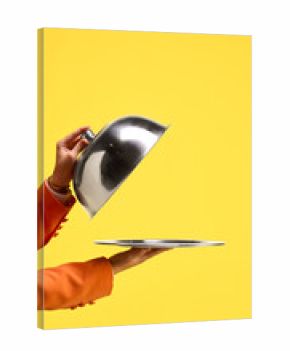 Silver cloche lifted to reveal empty tray against yellow background. Concept of anticipation, mystery reveal, presentation without outcome, and symbolic expectation. Copy space for ads