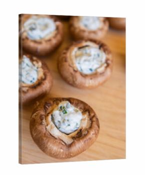 raw champignon mushrooms stuffed with herb cream cheese, arranged on a tray and ready to bake