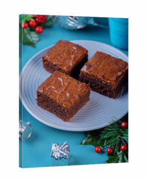 Dark chocolate brownie cakes in a plate on a blue background for Christmas holidays