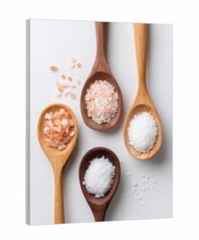 Flat lay of Celtic Salt vs other salt types in wooden spoons on light wood background, comparison scene