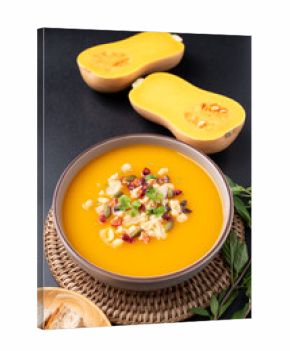 Butternut squash pumpkin soup with granola in a bowl on black background, Homemade food in autumn season