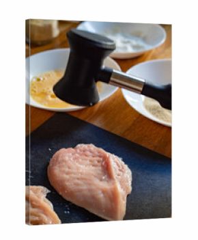 Cooking breaded chicken cutlets- pounding chicken breast, close-up