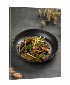 Savory beef stir fry with green onions, sesame and vegetables served in a black bowl