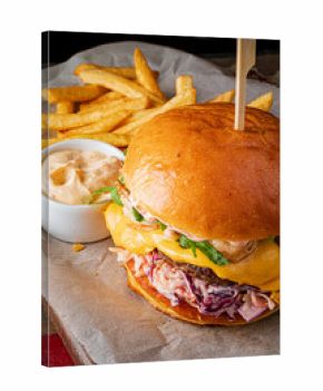 Tasty burger topped with cheese, greens, coleslaw, and served with fries and dip