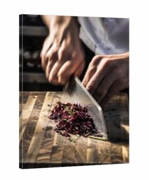 Skilled culinary professional precisely chopping purple cabbage with razor sharp knife on rustic wooden cutting board