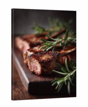 Perfectly seared lamb chops rest on a wooden board, garnished with fresh rosemary. Represents indulgence, fine dining, and culinary excellence. Ideal for food blogs and restaurants.