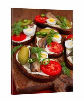 open sandwiches with sprats, vegetables and herbs, on a wooden board, breakfast, snack,