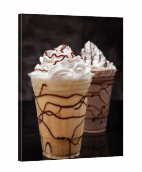 Vanilla milkshake with chocolate syrup in clear glass on dark background.