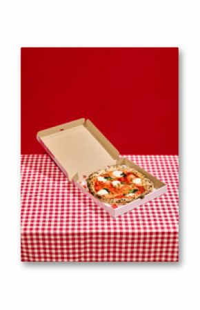 Open pizza box with delicious pizza on red checkered tablecloth against bold red background. Concept of food, pop art photography, hunger, visual satisfaction, food delivery services, restaurant menu