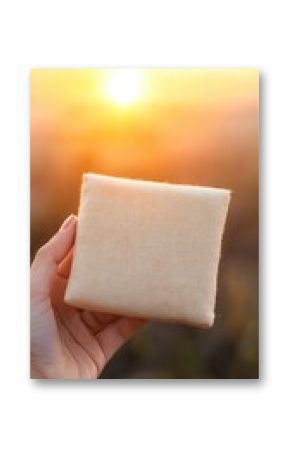 Hand Holding Cloth-Wrapped Food Package at Sunset