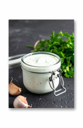 Glass jar of homemade ranch dressing with fresh herbs and garlic. Savory sauce for food.