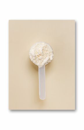 Plastic scoop filled with protein powder, placed on a plain beige surface,
