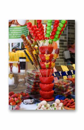 A colorful street food stall in Shanghai displays traditional Chinese candied fruits on sticks tanghulu