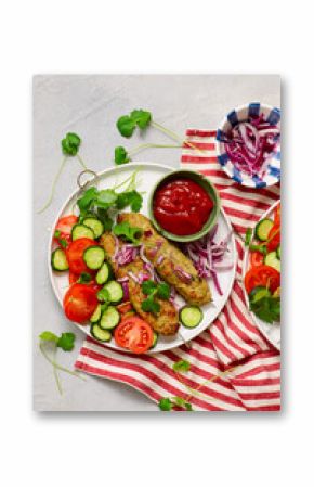 Chicken Lula Kebab with fresh vegetables and hot sauce on a platter.top veiw