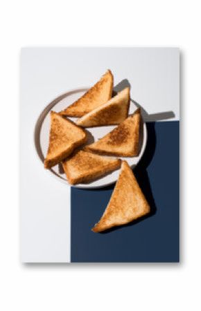 Triángulos de pan tostado dorado para sándwiches en un plato blanco sobre un fondo blanco y azul. Vista superior 