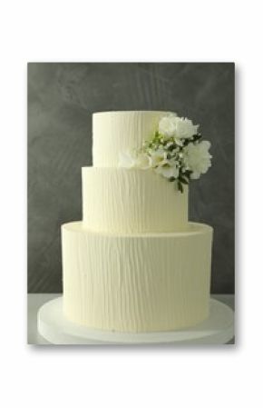 Delicious wedding cake with floral decor on table against grey background