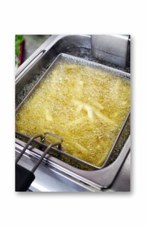 French fries cooking in boiling oil inside deep fryer