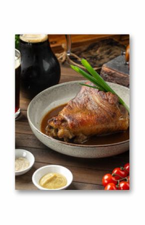 Portion of baked pork knuckle with sauce and spring onion