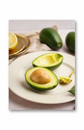 Plate with halves of fresh ripe avocado on white background