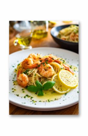Spaghetti with fried shrimps, olive oil and parsley on wooden table 