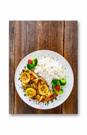 Lemon chicken escalopes with rice on wooden table