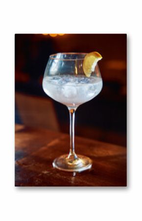 Chilled cocktail with lemon garnish in elegant wine glass on wooden bar