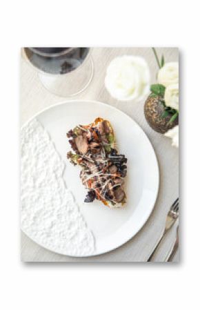 Bruschetta with roast beef and greens on white plate with wine