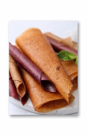 Delicious fruit leather rolls and mint on light table, closeup