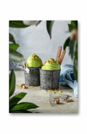 Pistachio Ice cream in two retro metal cups on textured background with greenery in frame
